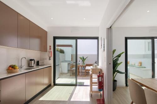 a kitchen with wooden cabinets and a dining room with a table at The Olive Tree Apartment in Tavira