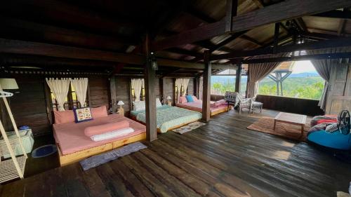 a room with two beds in a room with wood floors at Đen Hill Home The Wooden in Ðại Lào