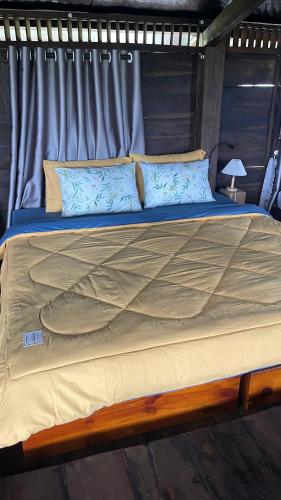 a large bed with blue pillows on top of it at Đen Hill Home The Wooden in Ðại Lào