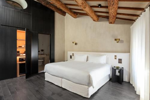 a bedroom with a large white bed and a bathroom at Palazzo Petrvs in Orvieto