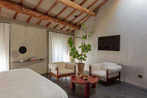 a bedroom with a bed and two chairs and a tv at Palazzo Petrvs in Orvieto