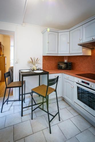 une cuisine avec des armoires blanches et une table et des chaises dans l'établissement Charmant F2 Wifi centre 3Pers, à Saint-Quentin