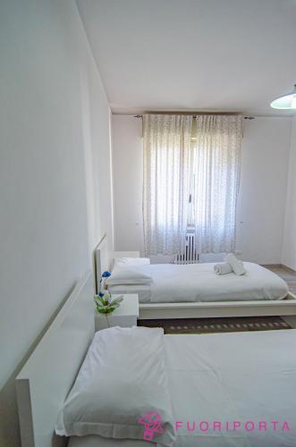 a white bedroom with two beds and a window at Casa di Stefania in Parma