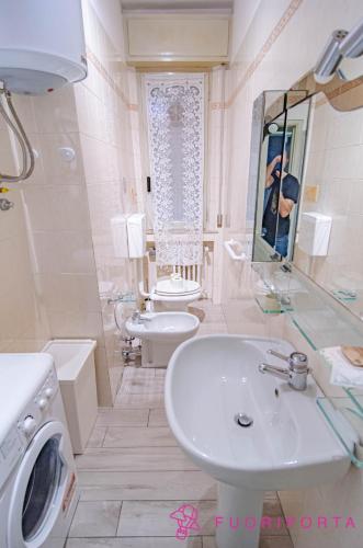 a white bathroom with a sink and a toilet at Casa di Stefania in Parma