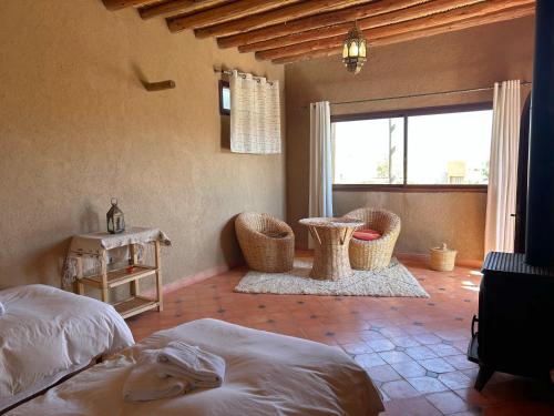 a bedroom with two beds and a table and a window at Les Jardins de la Santé in Tamazouzte