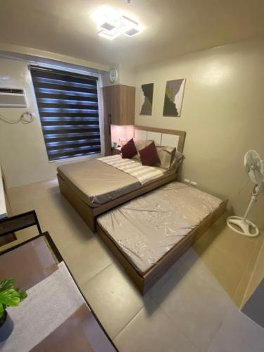 a bedroom with two beds and a window at Cozy studio unit 10mins from Airport 20mins from US Embassy across SM Sucat in Manila