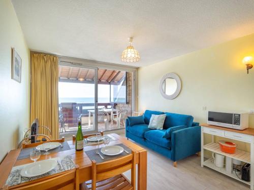 un salon avec un canapé bleu et une table dans l'établissement Carnac: Studio cosy 23m² près plage, parking, animal admis - FR-1-477-132, à Carnac