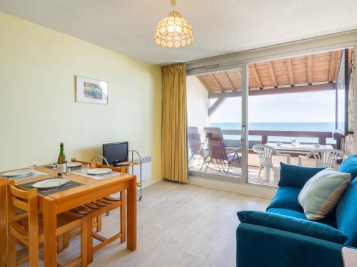 un salon avec un canapé bleu et une table dans l'établissement Carnac: Studio cosy 23m² près plage, parking, animal admis - FR-1-477-132, à Carnac