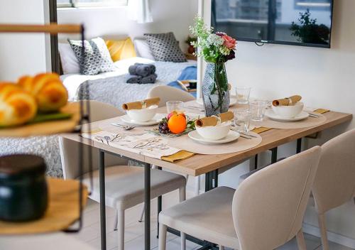 a dining room table with a vase of flowers on it at Asakusabashi Condominium Hotel in Tokyo
