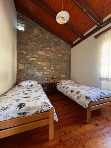 a bedroom with two beds and a stone wall at Bordon wines, estate with accommodation in Dekani