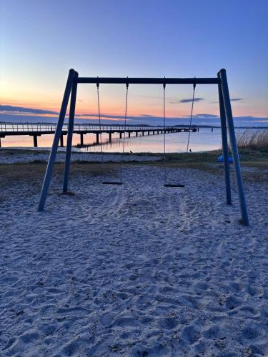 a swing set on the beach with a pier in the background at App 14 Entspannen im Wellengang! in Dranske