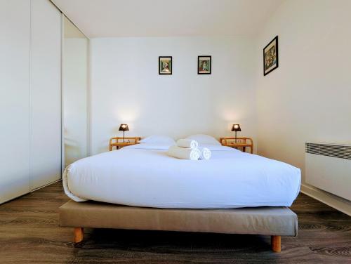 a bedroom with a large white bed with two lamps at Chic and comfortable apart with Parking and Terrace in Asnières-sur-Seine