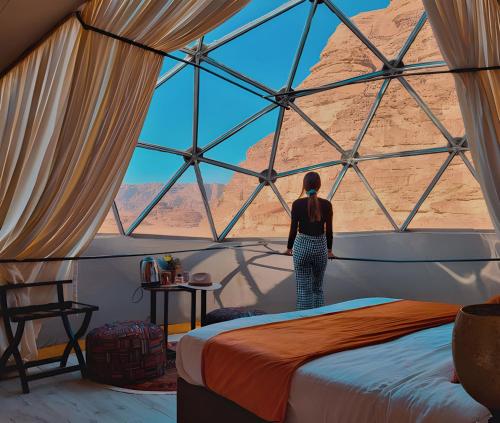 a woman standing in a room with a large window at Sofia Valley Camp in Wadi Rum
