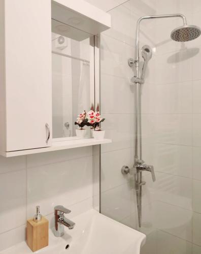 a white bathroom with a shower and a sink at Urban Retreat in Osijek