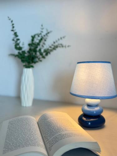an open book on a table next to a lamp at Sunset Escape Apartment - panoramic terrace in Fiumicino