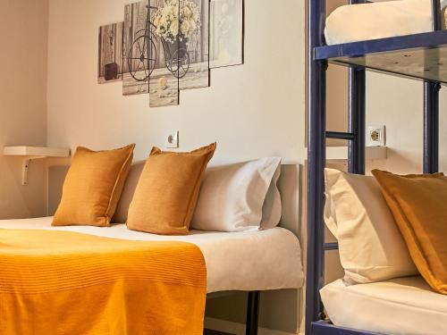 a bed with orange and white pillows in a room at Sun & Moon Hostel in Barcelona