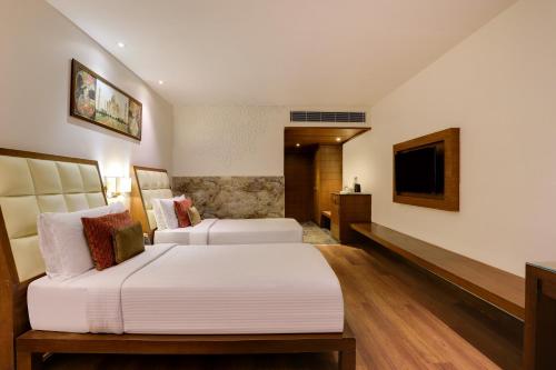 a hotel room with two beds and a television at Saura Hotel, Agra - A Club Mahindra Associate in Agra