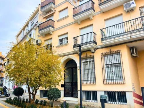 a large yellow building with balconies on a street at Home4u Acogedor apartamento en Maracena in Maracena