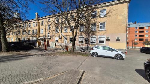 a white car parked in a parking lot in front of a building at Jaukus butas-studio Mažvydo al in Klaipėda
