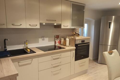 ロヴィニにあるAUGUSTINA Apartmentsの白いキャビネットとステンレス製の冷蔵庫を備えたキッチン