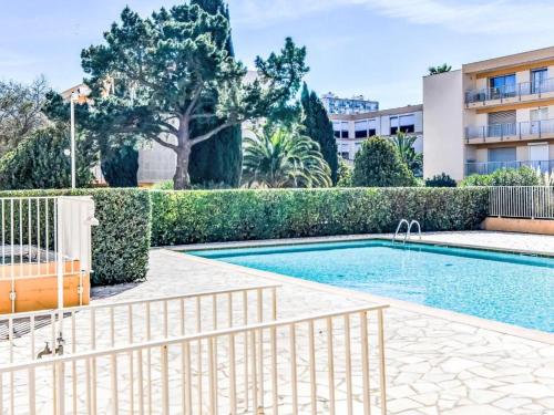 une piscine avec une clôture à côté d'un bâtiment dans l'établissement Cyclades Appartement dans Résidence Piscine Tennis Boulodrome, au Lavandou