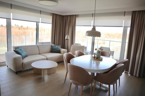 a living room with a couch and a table with chairs at POLANKI AQUA Apartamenty PREMIUM - w cenie nielimitowany dostęp do strefy Aqua in Kołobrzeg