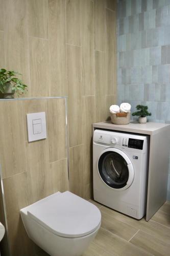 a bathroom with a toilet and a washing machine at POLANKI AQUA Apartamenty PREMIUM - w cenie nielimitowany dostęp do strefy Aqua in Kołobrzeg