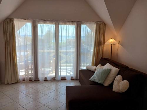 a living room with a couch and a large window at Lent a Parton Apartmanház in Balatonudvari