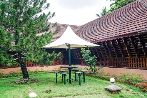 a picnic table with an umbrella in a yard at Palette - Pagoda Resorts in Cochin