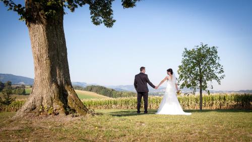a bride and groom holding hands next to a tree at Mostlandhof in Purgstall