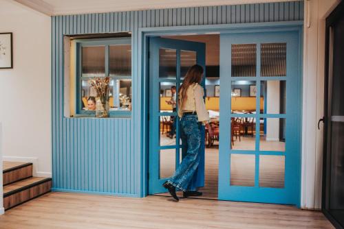 a woman is walking through a blue door at Hotel Puerta del Sur in Valdivia