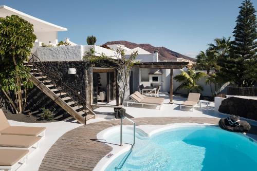 a swimming pool with chairs and a house at Kamezí Boutique Hotel Villas in Playa Blanca