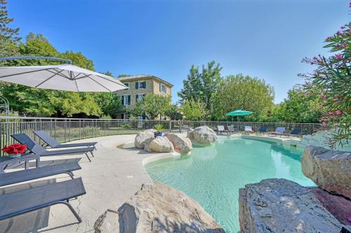 une piscine avec deux chaises et un parasol dans l'établissement La Bastide des Princes, Indoor and Outdoor Pools, à Caderousse