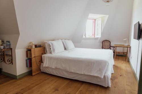 a bedroom with a white bed and a wooden floor at Chalet Ficalho in Cascais