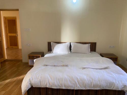 a bedroom with a large white bed with towels on it at Mamogang Home Stay in Leh