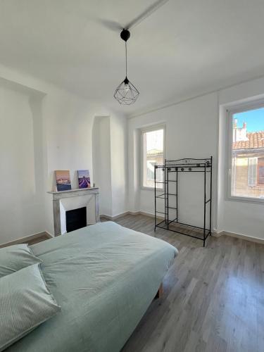 une chambre blanche avec un lit et une cheminée dans l'établissement Charmant T3 au cœur de la ville, à Marseille