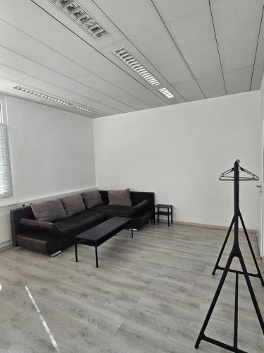 a living room with a black couch and a white wall at Bright, comfy, industrial looking in Fällanden