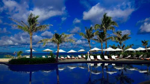 名護的住宿－布森納陽台酒店，棕榈树和遮阳伞度假村的游泳池