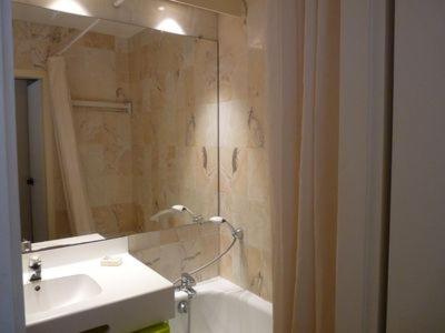 une salle de bain avec un lavabo, une baignoire et un miroir dans l'établissement Vue sur Marina, à La Rochelle