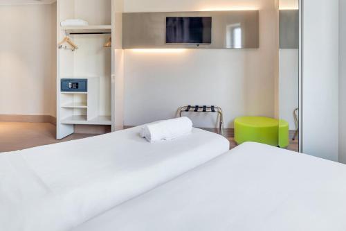 two beds in a room with a tv on the wall at B&B Hotel Milano San Siro in Milan
