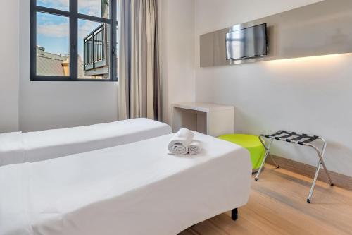 a room with two beds and a table and a chair at B&B Hotel Milano San Siro in Milan