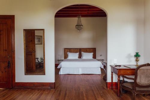 a bedroom with a bed and a mirror and a table at Chalet Ficalho in Cascais