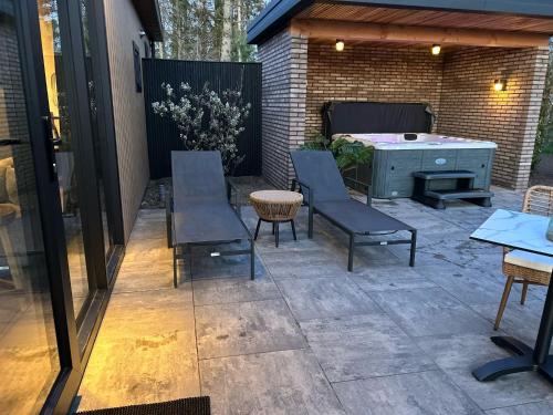 a patio with chairs and a table and a tub at Wellnesslodge Kievit in Dalerveen