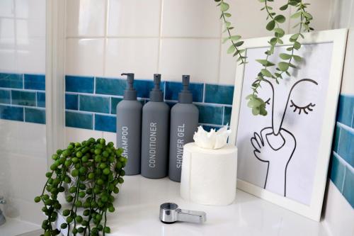 eine Badezimmertheke mit vier Flaschen darauf in der Unterkunft Hope Cottage In Slough With Parking in Slough