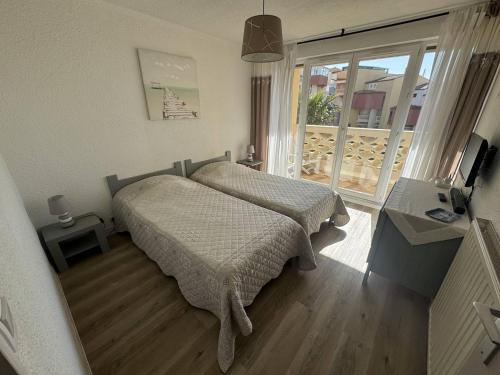 une chambre avec deux lits et un balcon dans l'établissement Bel appartement T2 au Cap d'Agde avec terrasse, parking, proche plage - FR-1-749-31, au Cap d'Agde