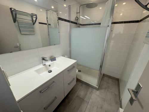 une salle de bain blanche avec un lavabo et une douche dans l'établissement Bel appartement T2 au Cap d'Agde avec terrasse, parking, proche plage - FR-1-749-31, au Cap d'Agde