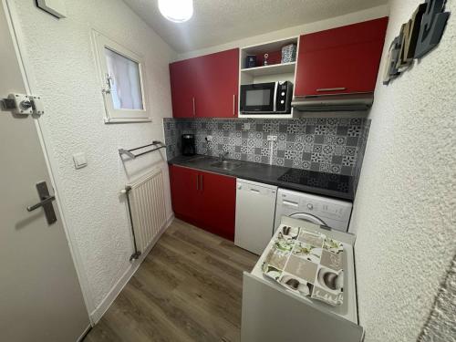 - une petite cuisine avec des armoires rouges et des appareils blancs dans l'établissement Bel appartement T2 au Cap d'Agde avec terrasse, parking, proche plage - FR-1-749-31, au Cap d'Agde