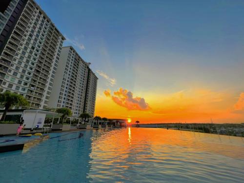a swimming pool with the sun setting behind buildings at BIG Two Bedrooms 1-6 Pax Luxury Condo at D Secret Garden - Johor Bahru-Setia Tropika-UTM-Mid Valley-Paradigm Mall in Johor Bahru