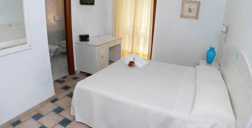 um quarto com uma cama branca e uma casa de banho em Hotel Patti em Golfo Aranci