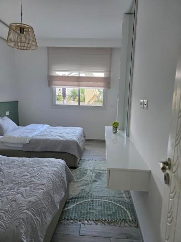 a bedroom with two beds and a table and a window at appartement Sarra Mahdia in Hiboun